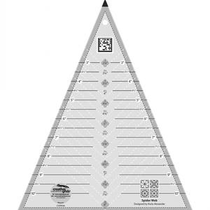 May include: A white triangle-shaped quilting ruler with black markings. The ruler is marked with inches and fractions of inches. The ruler is labeled "Spider Web" and "Designed by Karla Alexander".
