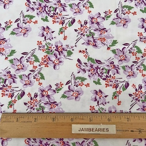 May include: White fabric with a repeating pattern of purple and orange flowers. The fabric is measured with a ruler that reads "JAMBEARIES".