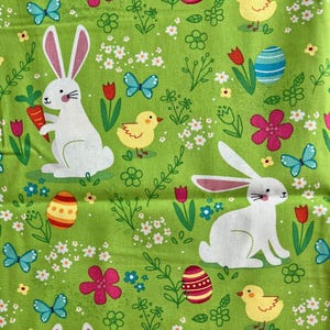 May include: A green fabric with a repeating Easter-themed pattern. The design includes white rabbits, yellow chicks, colorful eggs, butterflies, flowers, and tulips. The overall aesthetic is bright and cheerful.