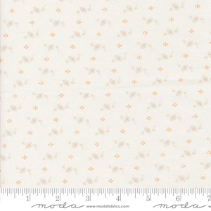 May include: Cream-colored fabric with a repeating pattern of small, stylized floral and dot designs in light brown and orange. The fabric has a ruler printed along the bottom edge, with the word "moda" printed at intervals.