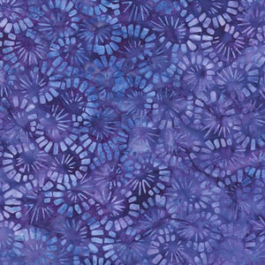 May include: A close-up of a fabric with a repeating pattern of blue and purple circular shapes. The design features a batik style with a mottled appearance, creating a textured and artistic look. The color palette is dominated by shades of indigo and violet.