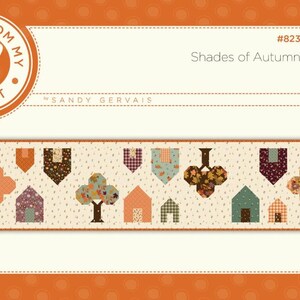 May include: A fabric banner with a repeating pattern of houses, trees, and pennants in autumn colors. The banner is labeled "Shades of Autumn" and includes the text "Pieces From My Heart".