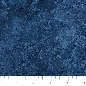 May include: A close-up of a textured fabric with a mottled appearance in shades of dark blue. The fabric has a marbled effect, with lighter blue and white accents. The image includes a ruler at the bottom, showing measurements in inches.