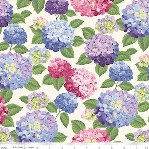 May include: A fabric pattern featuring a repeating floral design of hydrangea blooms in shades of blue, purple, pink, and green. The flowers are set against a cream-colored background, with green leaves. The pattern is approximately 12 inches wide.