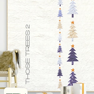 May include: A white quilt with a row of blue, white, and beige Christmas trees with orange stars. The quilt is titled "Those Trees 2" and is displayed on a wall with a wooden chair and wrapped gifts in front of it. The quilt is made by Zen Chic, Brigitte Heitland.