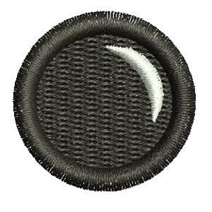 May include: A round, black embroidered patch featuring a textured background and a white, crescent-shaped design. The patch has a detailed, stitched border. The design is centrally placed within the circle.