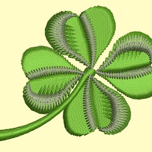 May include: Embroidered four-leaf clover in shades of green and gray, with a light yellow background. The clover's leaves are detailed with textured stitching, and the stem curves gently to the left. A symbol of luck and St. Patrick's Day.