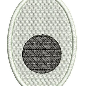 May include: Oval-shaped embroidered patch featuring a light gray background with a textured pattern. A black circle is centered within the oval. The patch is outlined with a white border.