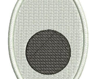 May include: Oval-shaped embroidered patch featuring a light gray background with a textured pattern. A black circle is centered within the oval. The patch is outlined with a white border.