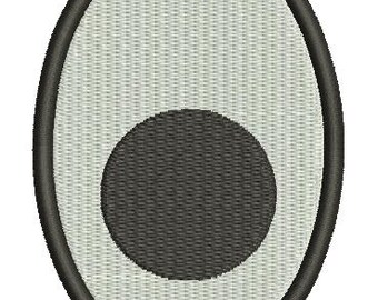 May include: An embroidered patch featuring an oval shape with a black border. The interior has a light gray woven texture, with a dark gray circle in the center. The patch is likely for clothing or accessories.