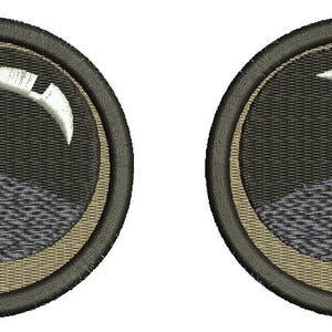 Può includere: Due toppe rotonde ricamate con un designo in bianco e nero. Il design presenta una forma di luna crescente con un contorno bianco e un piccolo cerchio bianco al centro. Le toppe sono circondate da un anello beige e da un anello esterno nero.