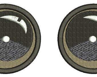 May include: Two round, embroidered patches with a black and white design. The design features a crescent moon shape with a white outline and a small white circle in the center. The patches are surrounded by a beige ring and a black outer ring.