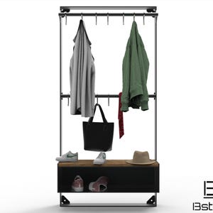Puede incluir: Un perchero de metal negro con un estante de madera y un estante de almacenamiento de metal negro debajo. El perchero tiene ganchos para colgar abrigos y una corbata colgando de uno de los ganchos. Hay dos pares de zapatos en el estante y un sombrero en el estante superior. El perchero está etiquetado como "BE Bstructte".