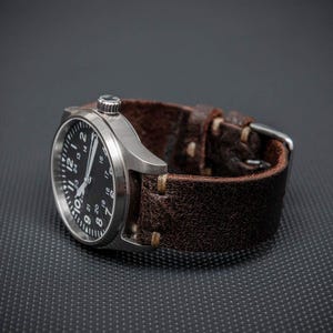 May include: A stainless steel wristwatch with a black face and white numerals. The watch has a brown leather strap with a silver buckle. The watch is a classic design, suitable for everyday wear.