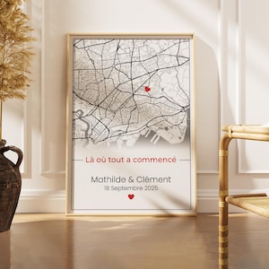 Può includere: Stampa su mappa incorniciata con una mappa della città in tonalità di grigio. Un cuore rosso indica una posizione specifica. Il testo "Là où tout a commencé" è sopra i nomi "Mathilde & Clément" e la data "18 Septembre 2025", con un cuore rosso sotto.