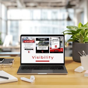 Pu&ograve; includere: Un laptop che mostra la parola "Visibilit&agrave;" in rosso. Lo schermo mostra tre diverse pagine web con testo e immagini. Una pianta in vaso, penne e blocchi per appunti sono sulla scrivania di legno.