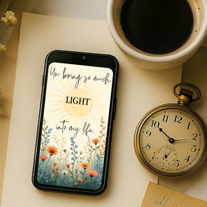 Puede incluir: Un smartphone muestra un diseño floral con las palabras "You bring so much LIGHT into my life." Un reloj de bolsillo dorado y una taza de café están cerca. El reloj marca las 10:09.