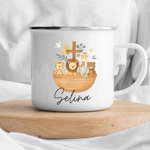 May include: White enamel mug featuring a watercolor illustration of animals in an ark, including a tiger, lion, giraffe, elephant, and bear. A wooden cross and the name "Selina" are also displayed on the mug.