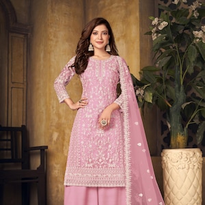 May include: A light pink embroidered salwar kameez ensemble. The outfit includes a long-sleeved tunic, wide-leg pants, and a matching sheer dupatta. The tunic and pants are adorned with intricate white embroidery. The number "241" is visible on the bottom left.