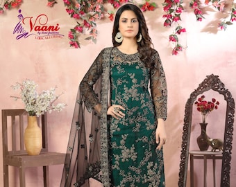 Può includere: Un salwar kameez verde smeraldo con ricami dorati intricati e un dupatta nero trasparente. L'outfit presenta un motivo floreale ed è abbinato a pantaloni coordinati. L'immagine include anche uno specchio decorativo e accenti floreali.
