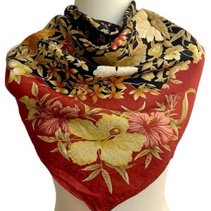 May include: A square silk scarf with a floral design. The scarf has a red border with large yellow and pink flowers. The centre of the scarf is black with a pattern of yellow, brown, and red flowers.