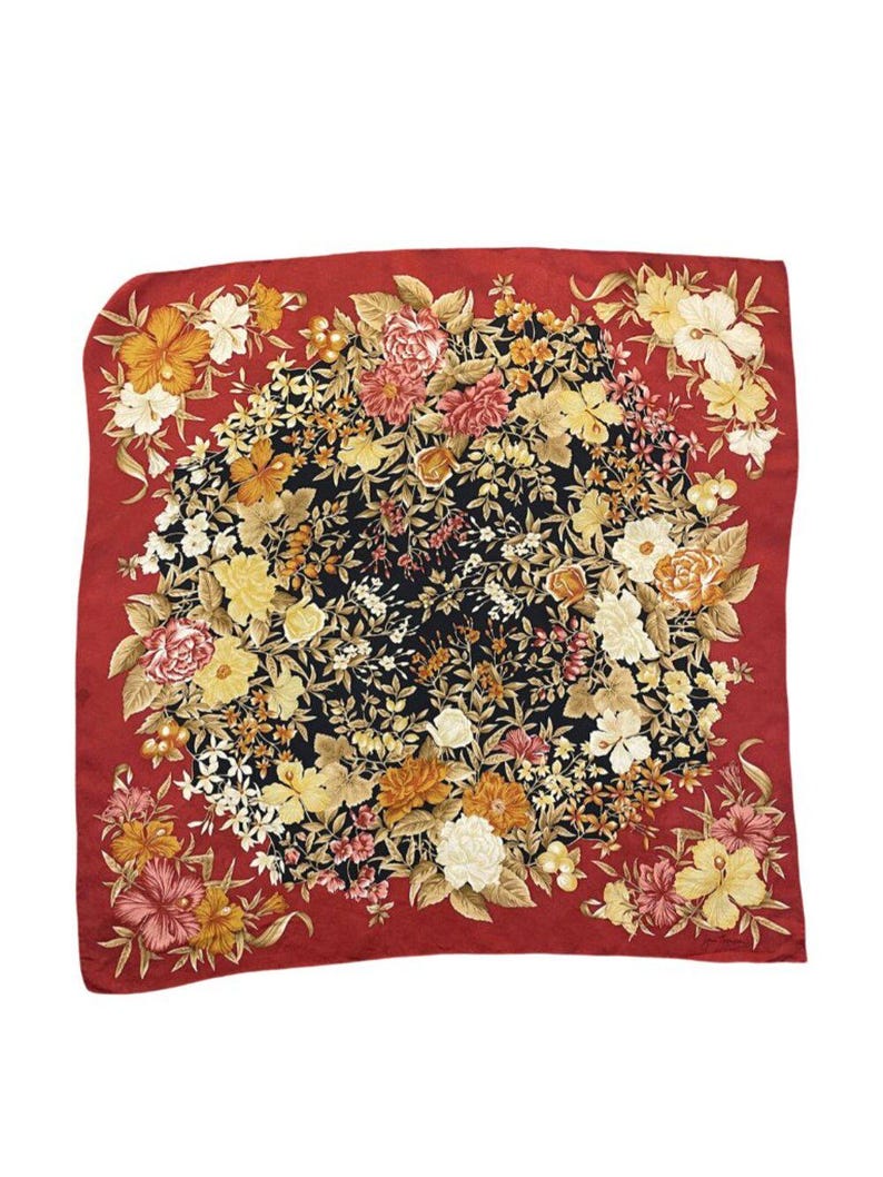 May include: A square silk scarf with a floral pattern. The scarf has a black centre with a vibrant arrangement of yellow, orange, pink, and white flowers. A red border frames the floral pattern. A fashion accessory.