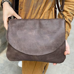 Kleine oder mittelgroße dunkelbraune Leder Umhängetasche für Frauen. Einfache Damentasche mit Klappe, handgefertigt aus natürlichem, weichem schokobraunem Leder