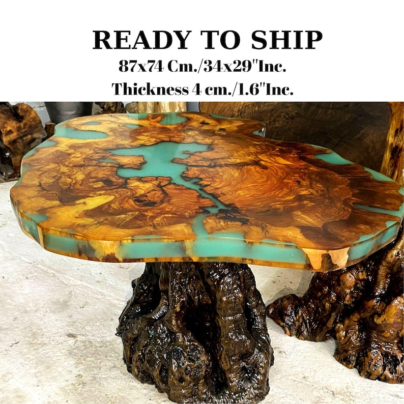 May include: A large, wooden coffee table with a natural, live edge design. The table top is made of wood with a turquoise blue epoxy resin fill. The table has a natural, tree root base. The table measures 34 inches by 29 inches and is 1.6 inches thick. READY TO SHIP.