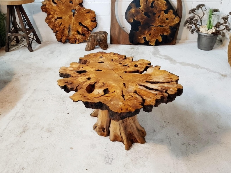 May include: A large, natural wood coffee table with a unique, irregular shape and a thick, sturdy base. The table top has a rich, brown color and a natural, rustic finish.