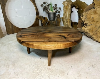 Può includere: Un tavolino da caffè rotondo in legno con un piano in legno marrone scuro e quattro gambe. Il tavolo è realizzato in legno riciclato e presenta una venatura unica.