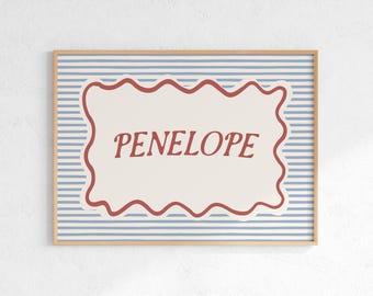 May include: A framed print with the name "PENELOPE" in a decorative font. The name is within a cream-coloured, wavy-edged shape, set against a blue and white striped background. The frame is a light brown colour.