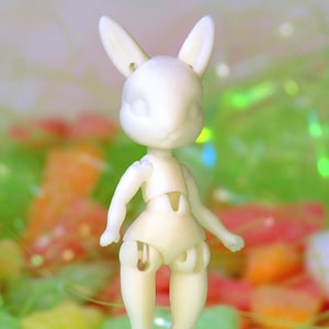 May include: A white plastic doll with bunny ears, standing on a bed of colourful jelly beans.