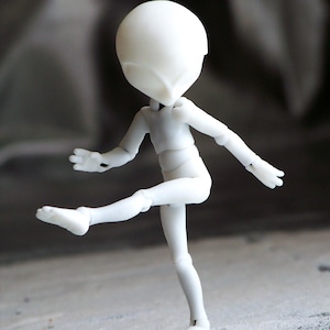 May include: A white articulated doll figure in a dynamic pose, with one leg raised and arms extended. The doll has a smooth, featureless head and body, with visible joints at the elbows, knees, and shoulders. The figure is set against a blurred, neutral background.