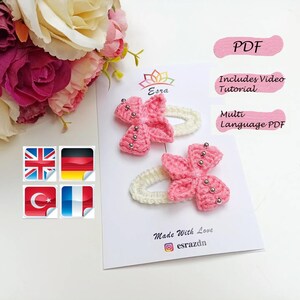 Puede incluir: Dos pinzas para el pelo de color rosa hechas a crochet con cuentas plateadas. Las pinzas están sobre un fondo blanco con el texto "Esra" y "Made With Love" en negro. El texto "PDF" está en rosa sobre un fondo blanco. Los textos "Includes Video Tutorial" y "Multi Language PDF" están en negro sobre un fondo blanco.