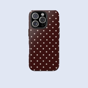 May include: A phone case with a dark brown background and a pattern of small, evenly spaced, light beige polka dots. The case has a camera module with multiple lenses.