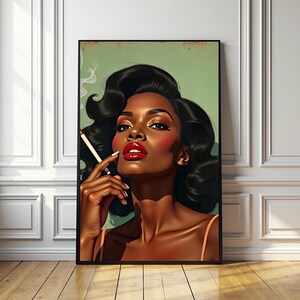 May include: A framed art print depicting a woman with dark skin, red lipstick, and a cigarette. The woman has dark, wavy hair and is set against a green backdrop. The artwork is framed in black and displayed on a wooden floor.