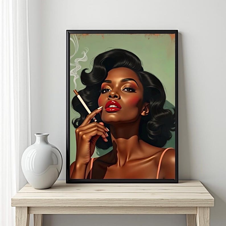 May include: A framed print of a woman with dark skin, red lipstick, and a cigarette. The woman has dark, wavy hair and is wearing a light pink top. The background is a muted green, and the frame is black.