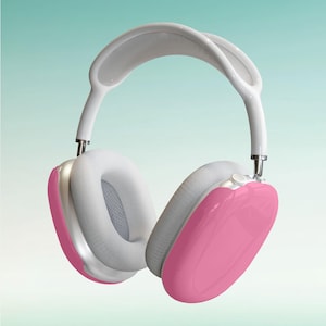May include: White and pink over-ear headphones with a padded headband and earcups. The earcups are covered in a soft, pink material.