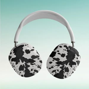 Puede incluir: Auriculares inalámbricos blancos con un diseño de estampado de vaca en blanco y negro.