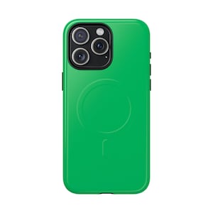 May include: A vibrant green phone case featuring a black camera module and black side buttons. The case has a circular indentation on the back, and a small, curved line below it. The phone case is designed to protect the phone.