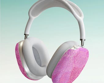 May include: White over-ear headphones with pink marbled earcups. The headphones have a white headband and ear cushions. The background is a gradient of light blue and green.