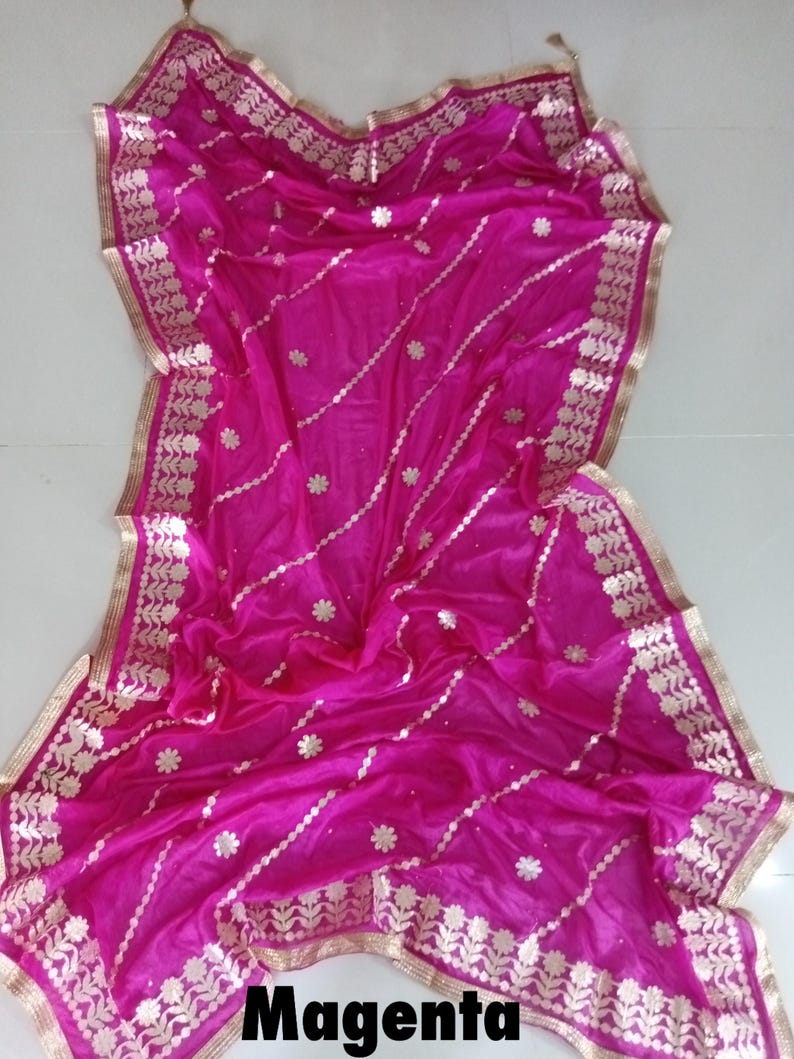 May include: A magenta silk dupatta with gold embroidery and a gold border. The dupatta has a floral design and is perfect for a special occasion.