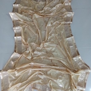 May include: A gold sequined sheer fabric with a gold border. The fabric is folded and draped on a white surface. The word "Gold" is written in black letters at the bottom of the image.