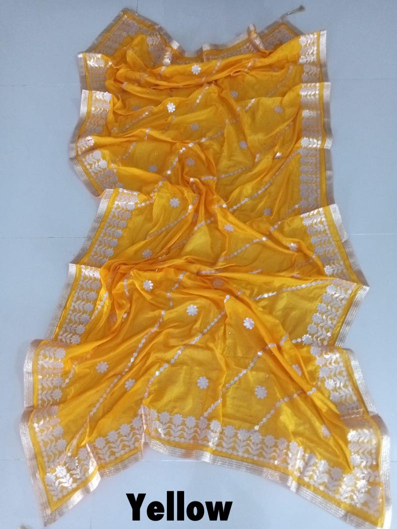 May include: A yellow sheer saree with a silver and gold embroidered border. The saree has a floral pattern and is perfect for special occasions.