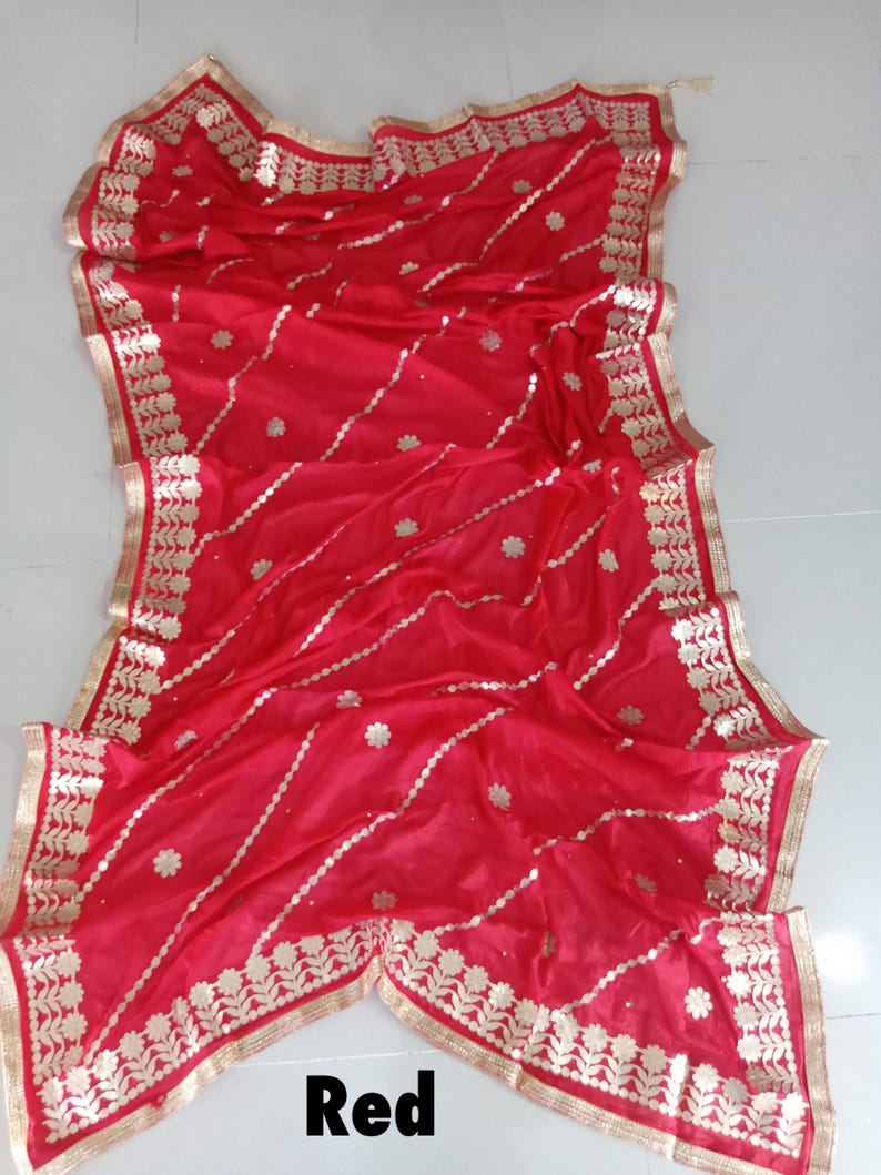 May include: Red saree with gold embroidery and a decorative border. The saree is made of a sheer fabric and has a delicate floral pattern.