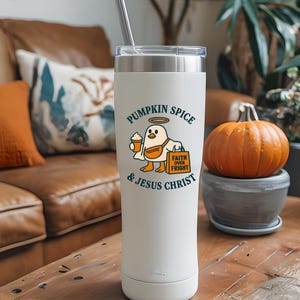 May include: A white insulated tumbler with a silver lid and straw. The tumbler features a graphic of a cartoon bird holding a pumpkin spice latte and a bag that says "Faith Over Fright." Text on the tumbler reads "Pumpkin Spice & Jesus Christ."