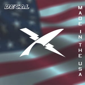 May include: White decal featuring a stylized design of a knife and lightning bolt, with the word "DECAL" in the upper left corner. The background is a blurred American flag with the text "MADE IN THE USA" vertically on the right.