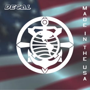 May include: White decal featuring an anchor design with a globe in the center, surrounded by a circular frame. The word "DECAL" is at the top left, and "MADE IN THE USA" is written vertically on the right. The background is an American flag.