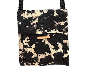 Bolsa artesanal tingida em preto e branco com efeito tie-dye e acabamento descolorido.