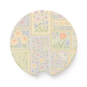 May include: A round, beige coaster with a patchwork design featuring various floral patterns in shades of pink, yellow, and blue. The coaster has a cutout in the bottom for easy gripping.